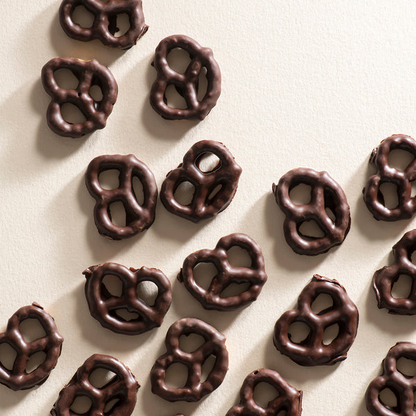 A collection of dark chocolate-coated pretzels arranged on a surface.