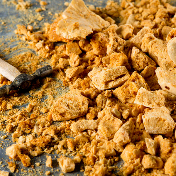 Crunchy golden honeycomb pieces scattered on a surface with a chisel in the mix, indicating the honeycomb's preparation or breaking process.